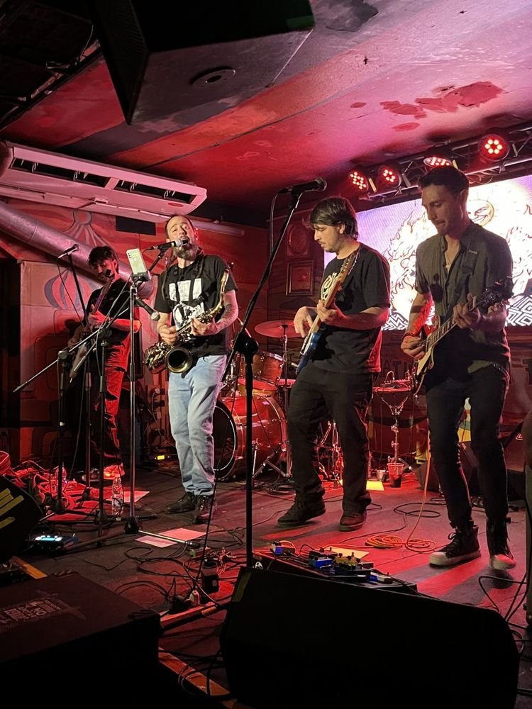 La banda tocando en vivo con saxo y guitarras