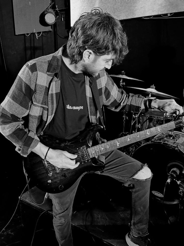 Guitarrista afinando junto a la batería